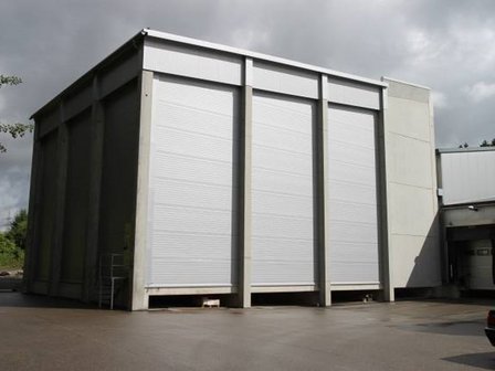 Photo of a modern warehouse building with roller doors and concrete walls.