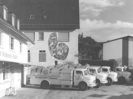 Historical photo of milk delivery lorries and a mural on the wall of the building.